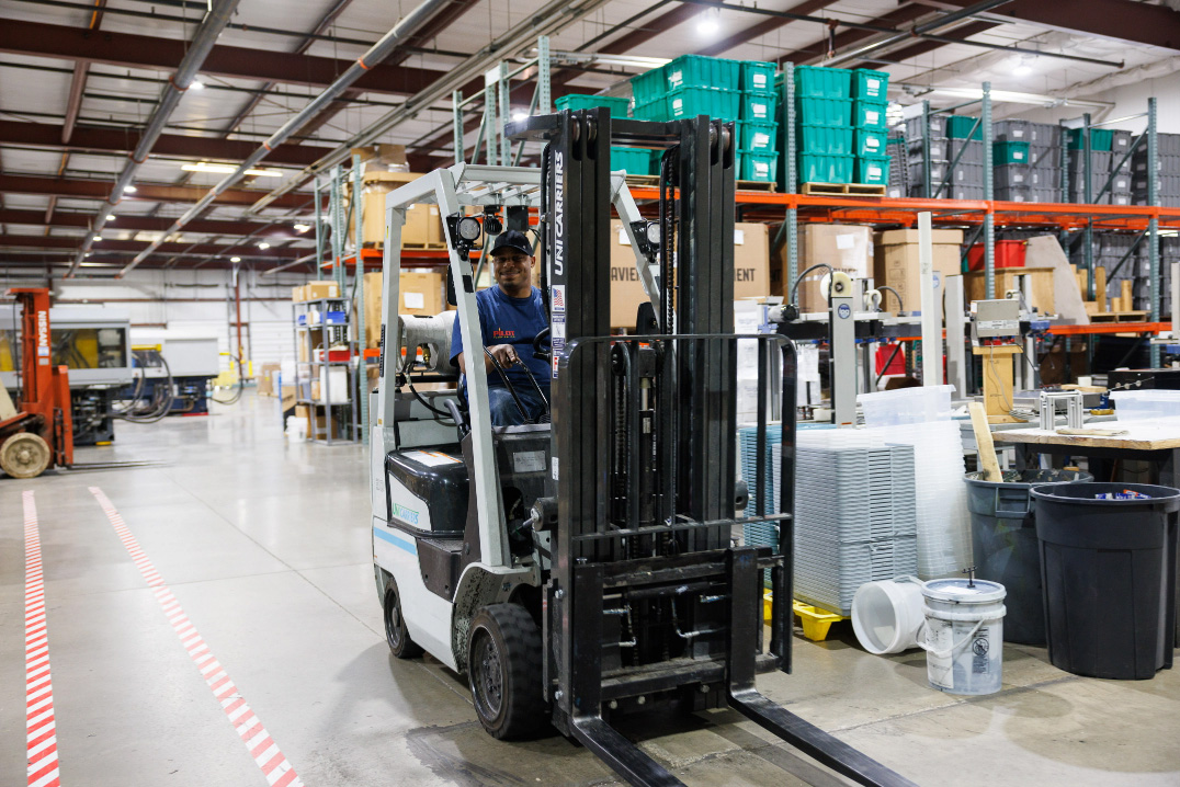 happy man operating a forklift in a clean factory