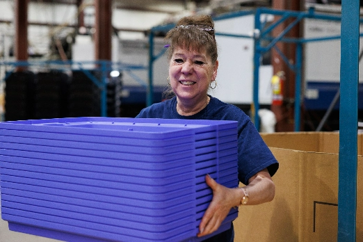 Happy woman carrying storage lids in a factory
